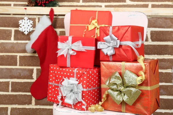 Різдвяні подарунки на стільці на фоні коричневої цегляної стіни — стокове фото