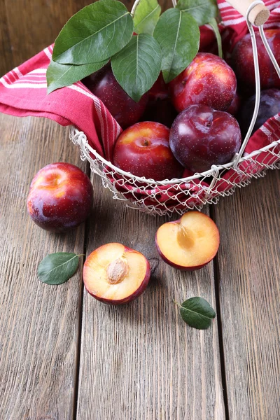 Sweet plums in wicker basket on wooden background — Stock Photo, Image