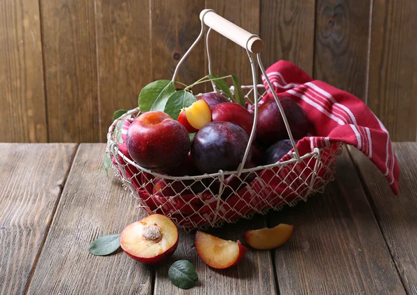Prugne dolci in cesto di vimini su fondo di legno — Foto Stock