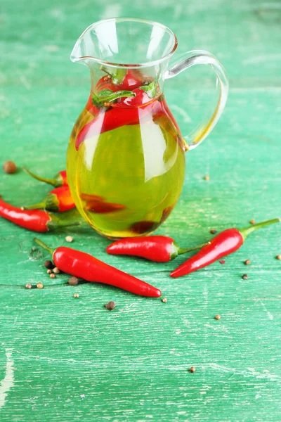 Huile d'olive naturelle infusée maison avec des piments rouges sur fond de bois de couleur — Photo