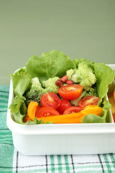 Tasty vegetarian food in plastic box on green wooden table — Stock Photo, Image