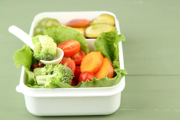 Sabrosa comida vegetariana en caja de plástico sobre mesa de madera verde —  Fotos de Stock