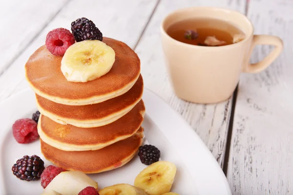 Crêpe aux fruits et baies sur assiette avec tasse de thé sur table en bois — Photo