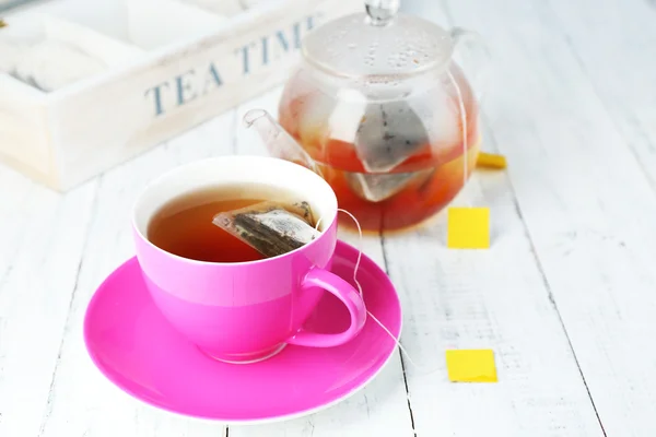 Csésze tea, teáskanna és tea táskák a fából készült asztal közelről — Stock Fotó