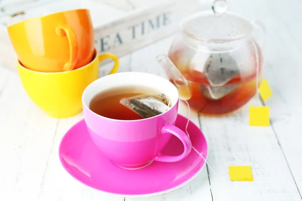 Xícara de chá, bule e sacos de chá em mesa de madeira close-up — Fotografia de Stock