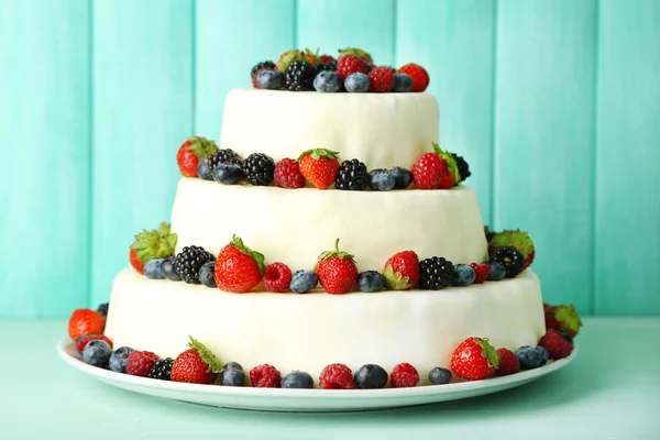 Beautiful wedding cake with berries on color wooden background — Stock Photo, Image