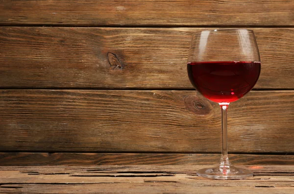 Glas rode wijn op houten tafel op houten muur achtergrond — Stockfoto