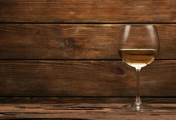 Glass of white wine on wooden table on wooden wall background — Stock Photo, Image