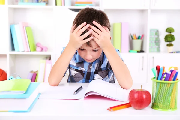 Schoolboy sitting at table in classroom — Stock Photo, Image