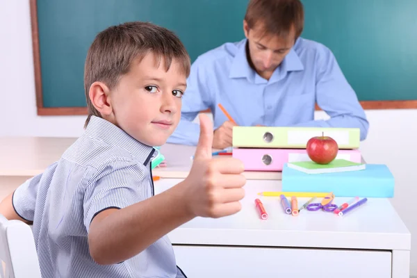 Skolpojke och lärare sitter i klassrummet på blackboard bakgrund — Stockfoto