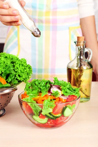 Vrouw zouten plantaardige salade in keuken — Stockfoto