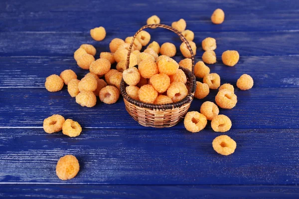 Raspberries in wicker basket on dark blue wooden background — Stock Photo, Image