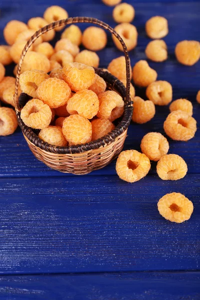 Raspberries in wicker basket on dark blue wooden background — Stock Photo, Image