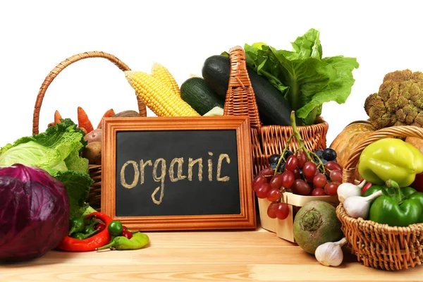 Fresh organic vegetables with chalkboard on wooden table, close up — Stock Photo, Image