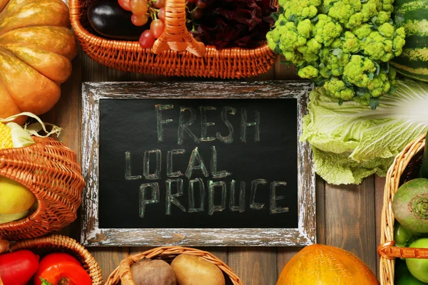Fresh organic vegetables with chalkboard on wooden table, close up — Stock Photo, Image