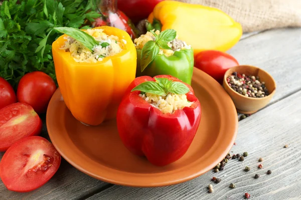 Composición con pimientos rellenos en plato y hierbas frescas, especias y verduras, sobre fondo de madera — Foto de Stock