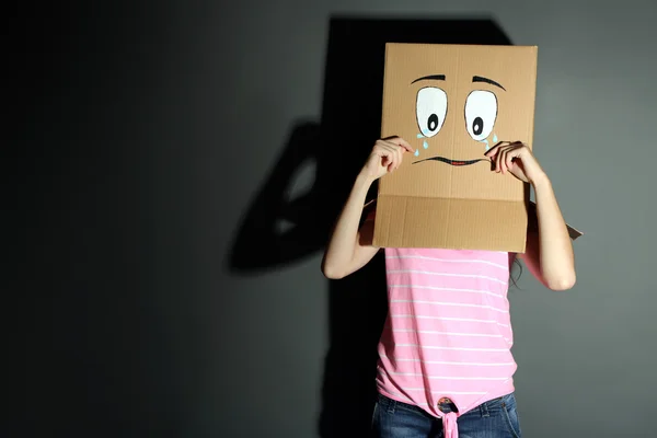 Femme avec boîte en carton sur la tête avec visage triste, sur fond gris — Photo