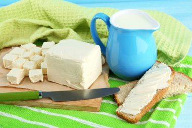 kesme tahtası ve renk ahşap arka plan üzerinde süt ile sürahi taze tereyağı