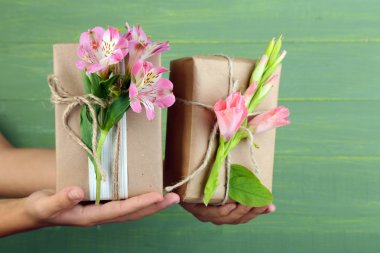 Kadın el doğal tarzı tutarak taze çiçekler ve ahşap arka plan üzerinde rustik sicim ile hediye kutuları el işi