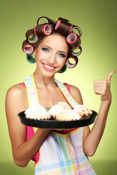 Beautiful girl in hair curlers on green background