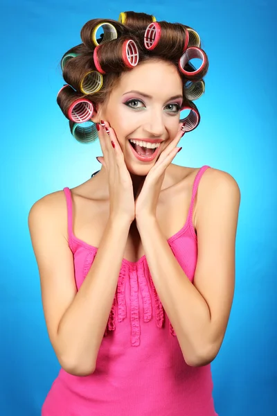 Menina bonita em encrespadores de cabelo no fundo azul — Fotografia de Stock