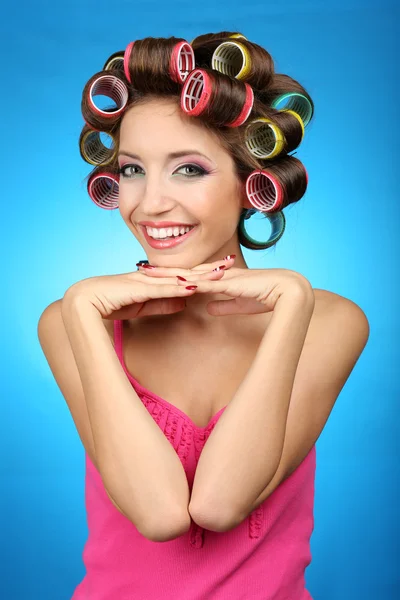 Menina bonita em encrespadores de cabelo no fundo azul — Fotografia de Stock