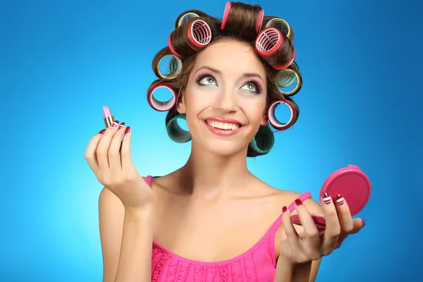 Beautiful girl in hair curlers on blue background — Stock Photo, Image