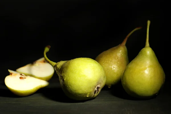 Las peras maduras sabrosas sobre la mesa de madera, sobre el fondo oscuro — Foto de Stock