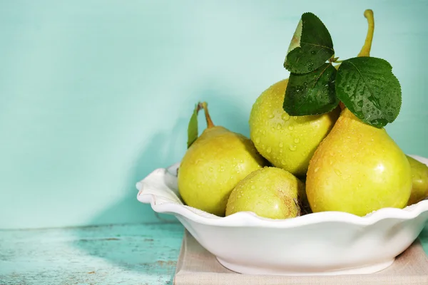 Ripe tasty pears in bowl, on wooden table — Stock Photo, Image