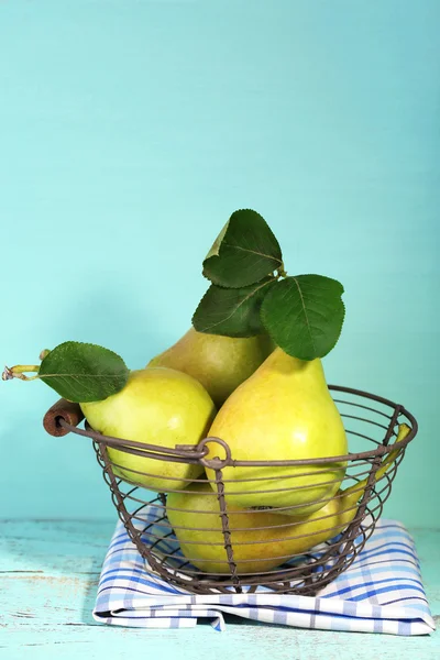 Ripe tasty pears in metal basket, on wooden table — Stock Photo, Image
