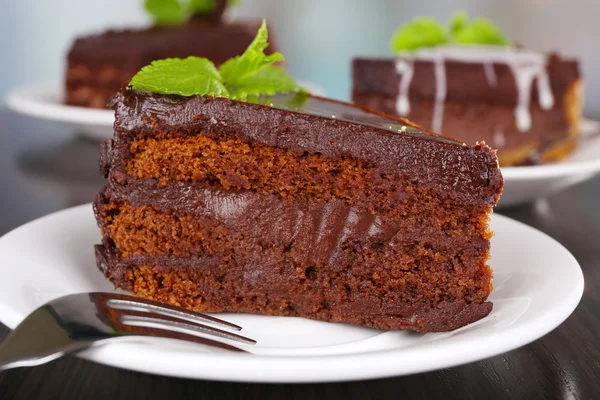 Stücke Schokoladenkuchen auf Tellern auf Holztisch vor natürlichem Hintergrund — Stockfoto