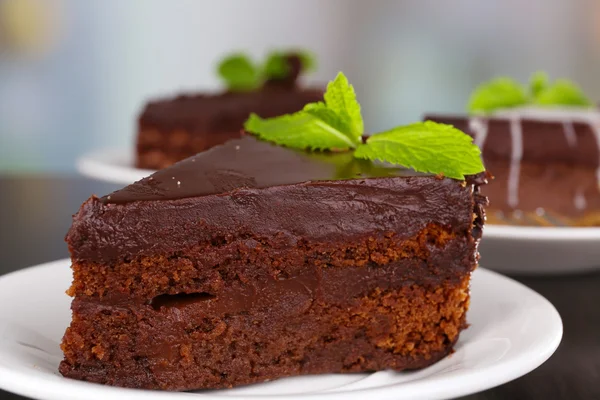 Trozos de pastel de chocolate en platos sobre mesa de madera sobre fondo natural —  Fotos de Stock