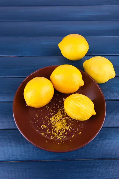 Lemons on plate on dark blue wooden background — Stock Photo, Image