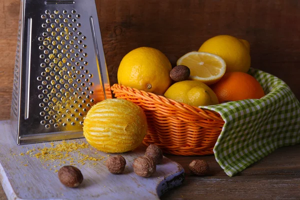 Cytryny w serwetkę w kosz, deska do krojenia i tarka na drewniane tła — Zdjęcie stockowe