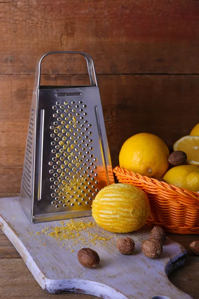 Citrons sur serviette dans le panier, planche à découper et râpe sur fond en bois — Photo