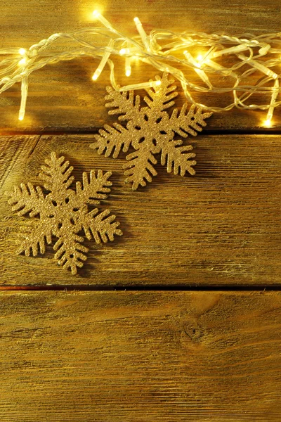 Garland and snowflakes on wooden background — Stock Photo, Image