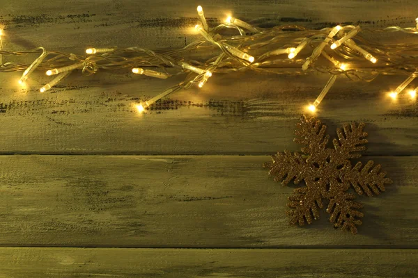 Garland and snowflake on wooden background — Stock Photo, Image