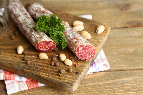 Salame italiano em tábua de corte de madeira, sobre fundo de madeira — Fotografia de Stock