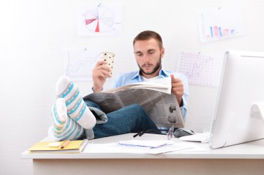 Masa üzerinde komik çoraplı bacaklarını tutan emin iş adamı