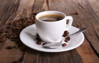 Ahşap arka planda bir fincan kahve ve fasulye.