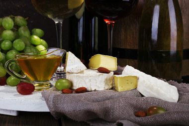 Camembert ve brie peyniri, bal, şarap ve üzüm çul stand ve şarap varil portre üzerinde oluşan akşam yemeği
