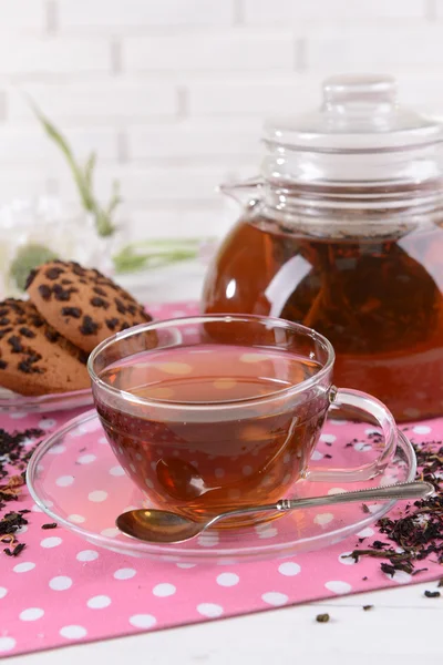 Чайник и чашка чая на столе на фоне кирпичной стены — стоковое фото