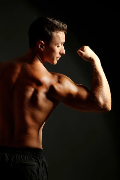 Красивый мускулистый молодой человек на темном фоне — стоковое фото