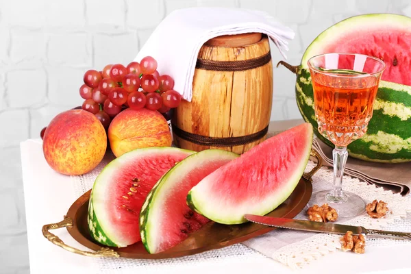 Composición de sandía madura, frutas, vino rosa en vaso y barril de madera sobre mesa de madera de color, sobre fondo claro —  Fotos de Stock