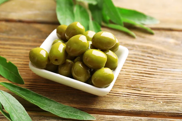 Olive verdi in ciotola con foglie in tavola primo piano — Foto Stock