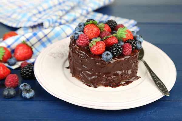 Smakelijke chocolate cake met verschillende bessen, op houten tafel — Stockfoto