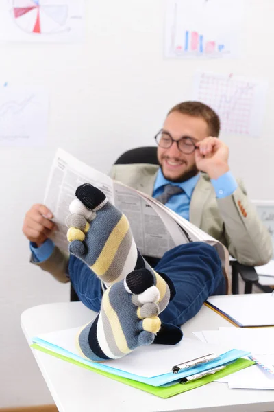 Confident businessman holding his legs in funny socks on desk — Stock Photo, Image