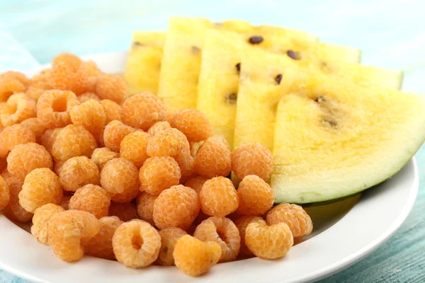 Slices of yellow watermelon and raspberry on plate on napkin closeup — Stock Photo, Image