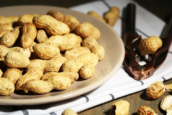 Cacahuetes en plato, sobre fondo de madera —  Fotos de Stock