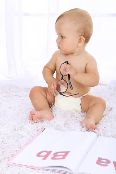 Cute baby boy with book on carpet in room — Stock Photo, Image